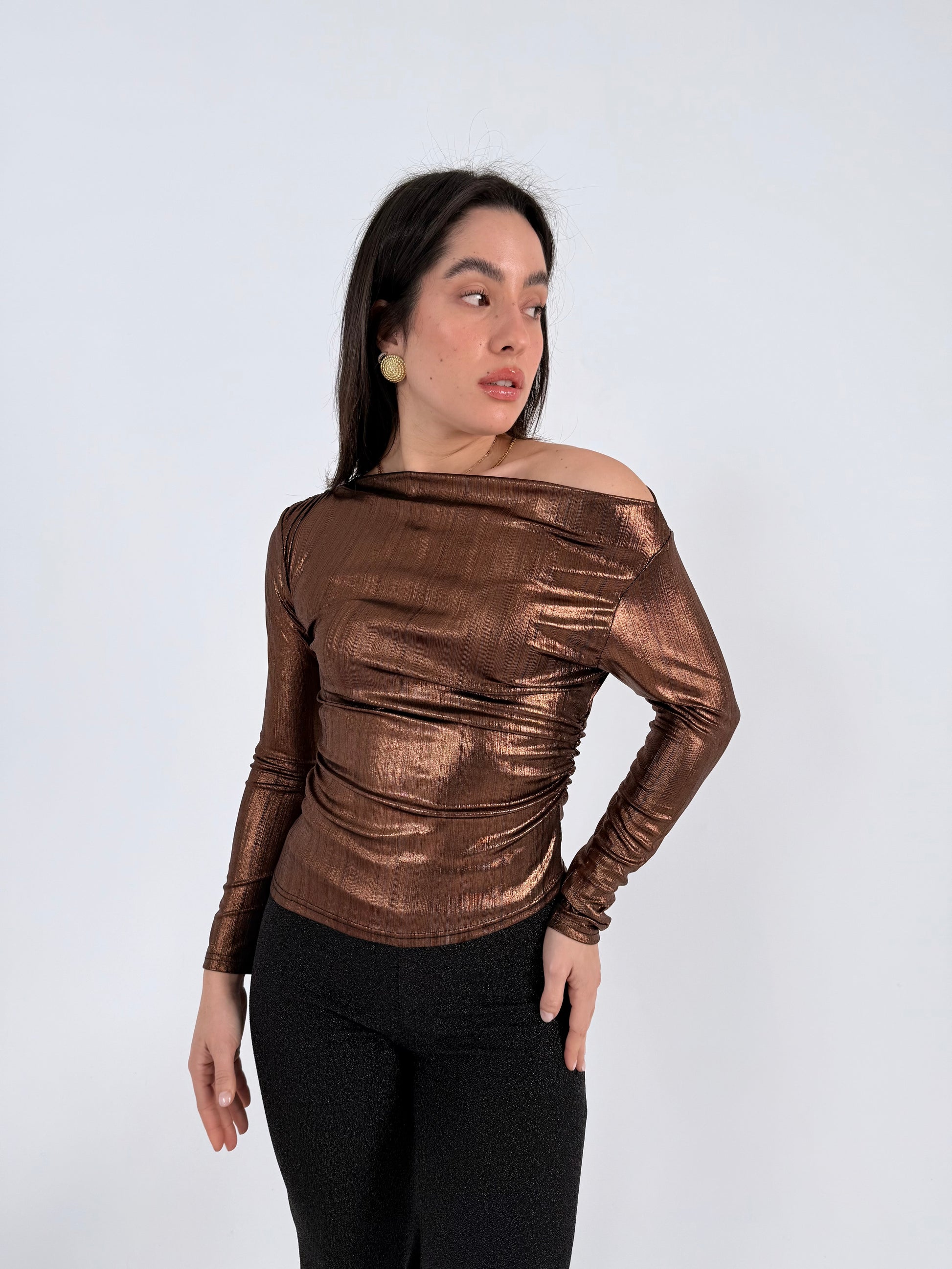 Woman wearing a bronze metallic top against a white background