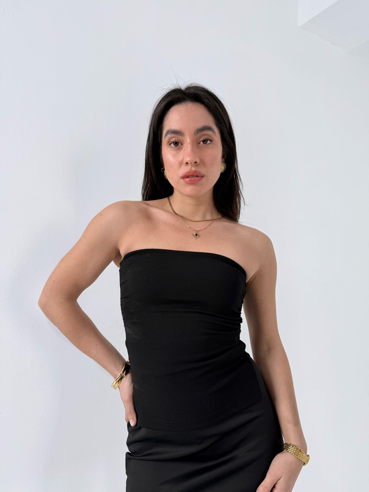 Woman wearing a black strapless top against a white background